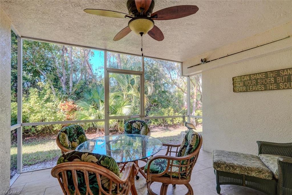 Sunroom featuring ceiling fan, outdoor dining space, and view of scattered trees