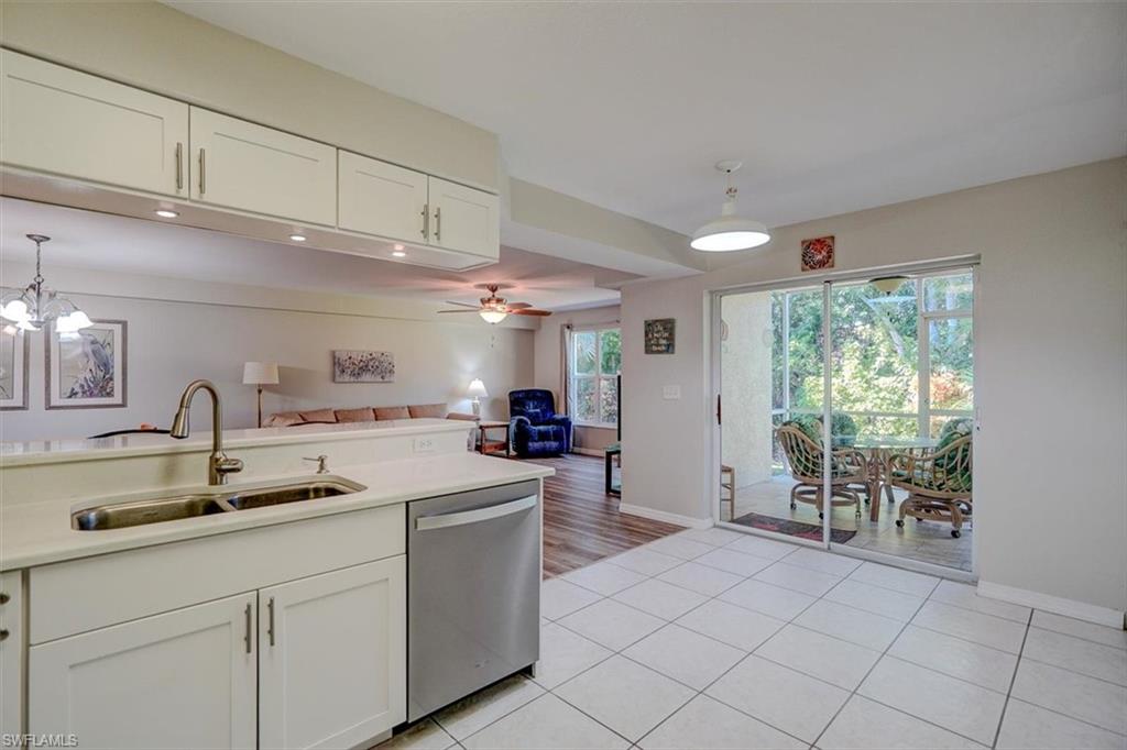 Kitchen featuring white cabinets, pendant lighting, light tile patterned floors, stainless steel dishwasher, and open floor plan
