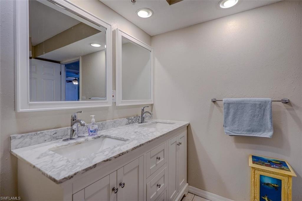 Bathroom featuring double vanity, a textured wall, recessed lighting, and light tile patterned flooring