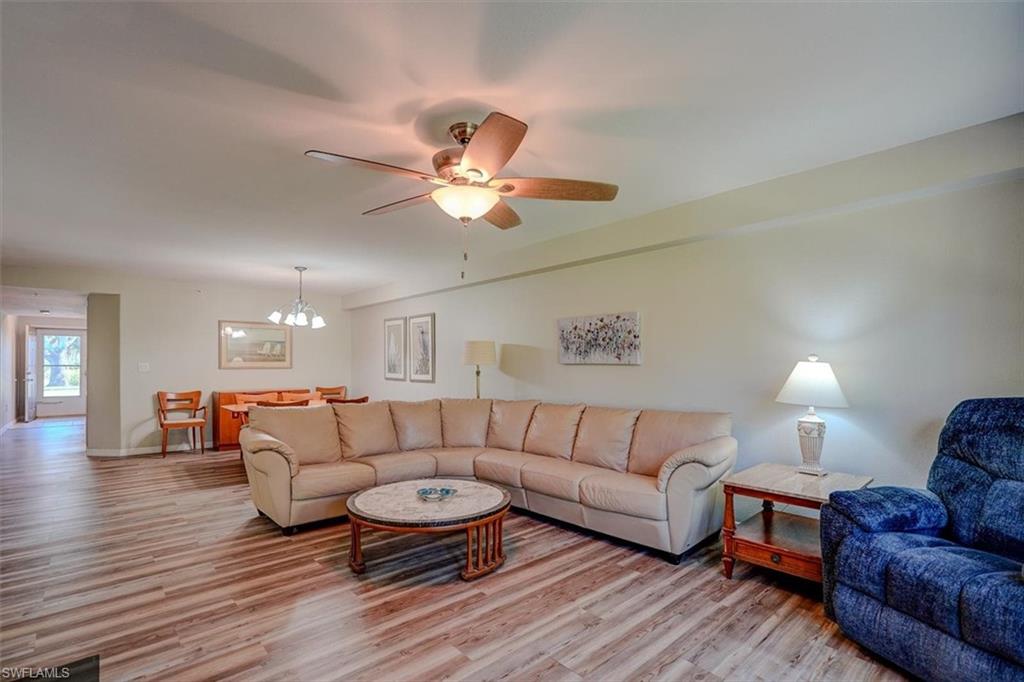 Living room featuring light wood-style floors, a chandelier, and a ceiling fan