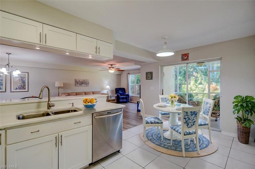 Kitchen featuring pendant lighting, white cabinetry, stainless steel dishwasher, light tile patterned floors, and open floor plan