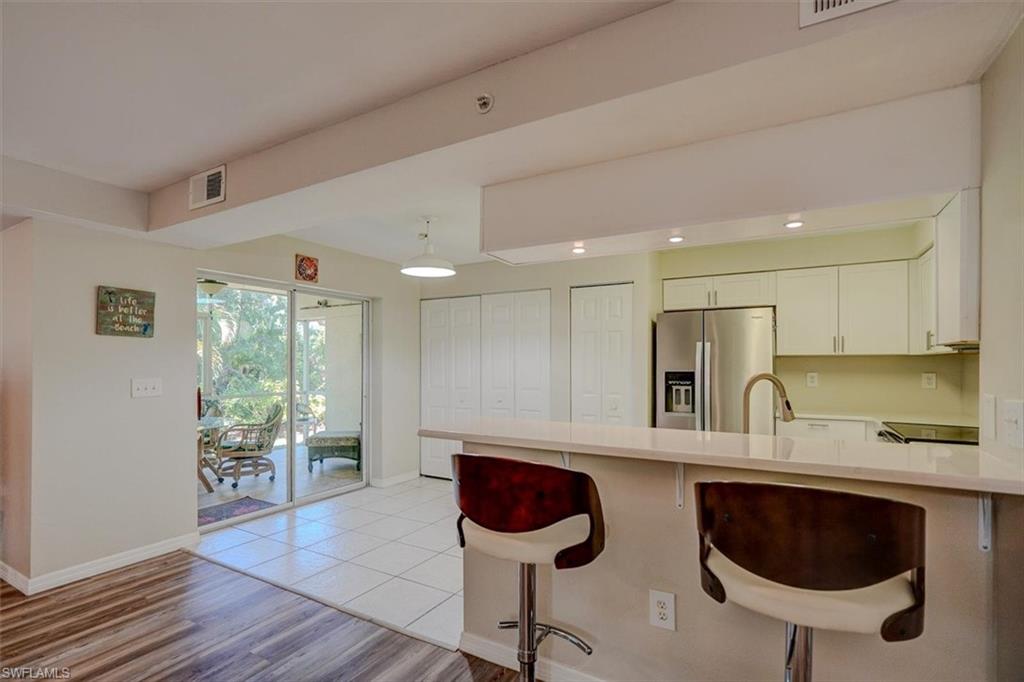 Kitchen featuring a breakfast bar area, a peninsula, stainless steel fridge, light wood-style flooring, and white cabinets