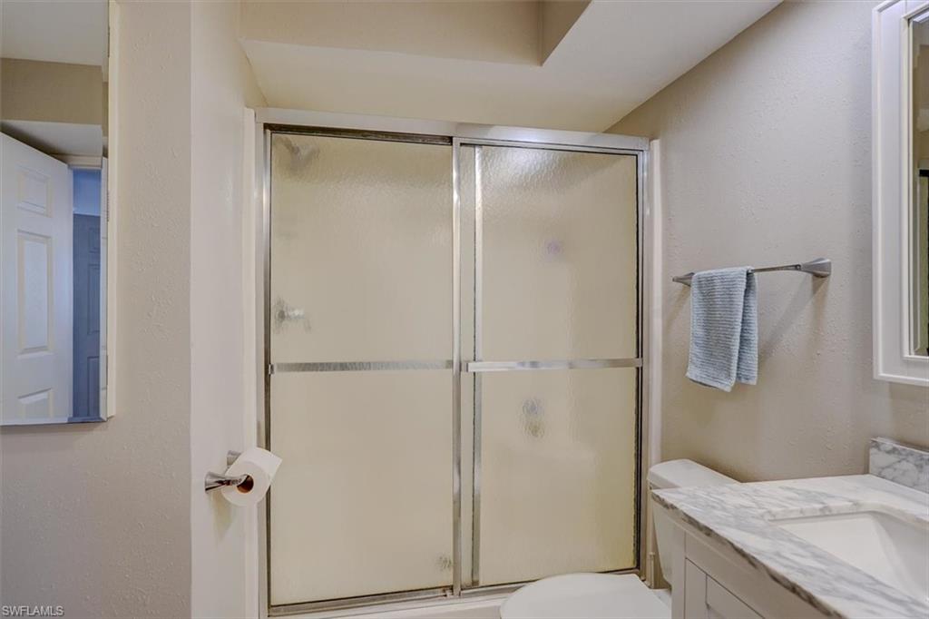 Bathroom with vanity, a textured wall, and a shower stall