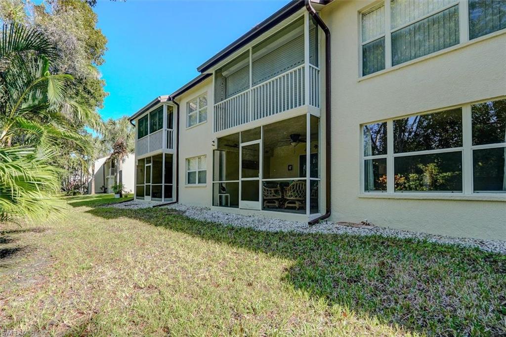 Back of house featuring a sunroom, a balcony, a yard, stucco siding, and ceiling fan