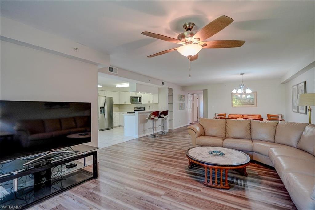 Living area with a chandelier, light wood-style flooring, and ceiling fan