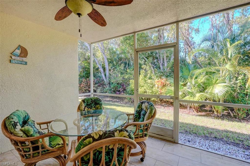 Sunroom / solarium with a ceiling fan, view of wooded area, and outdoor dining space