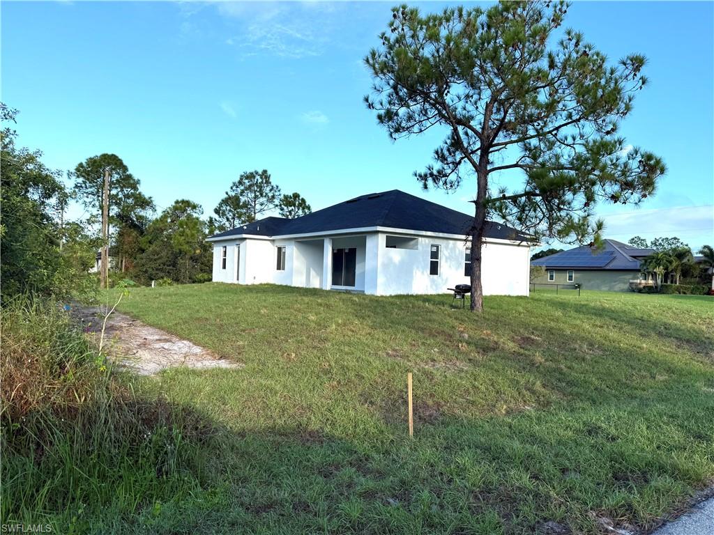 Rear view of property with a lawn and stucco siding