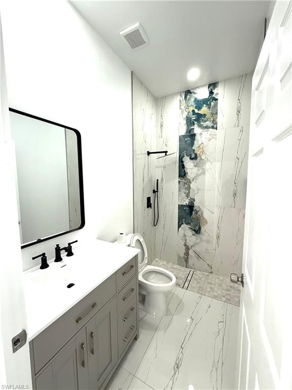 Bathroom featuring light marble finish flooring, vanity, and a marble finish shower