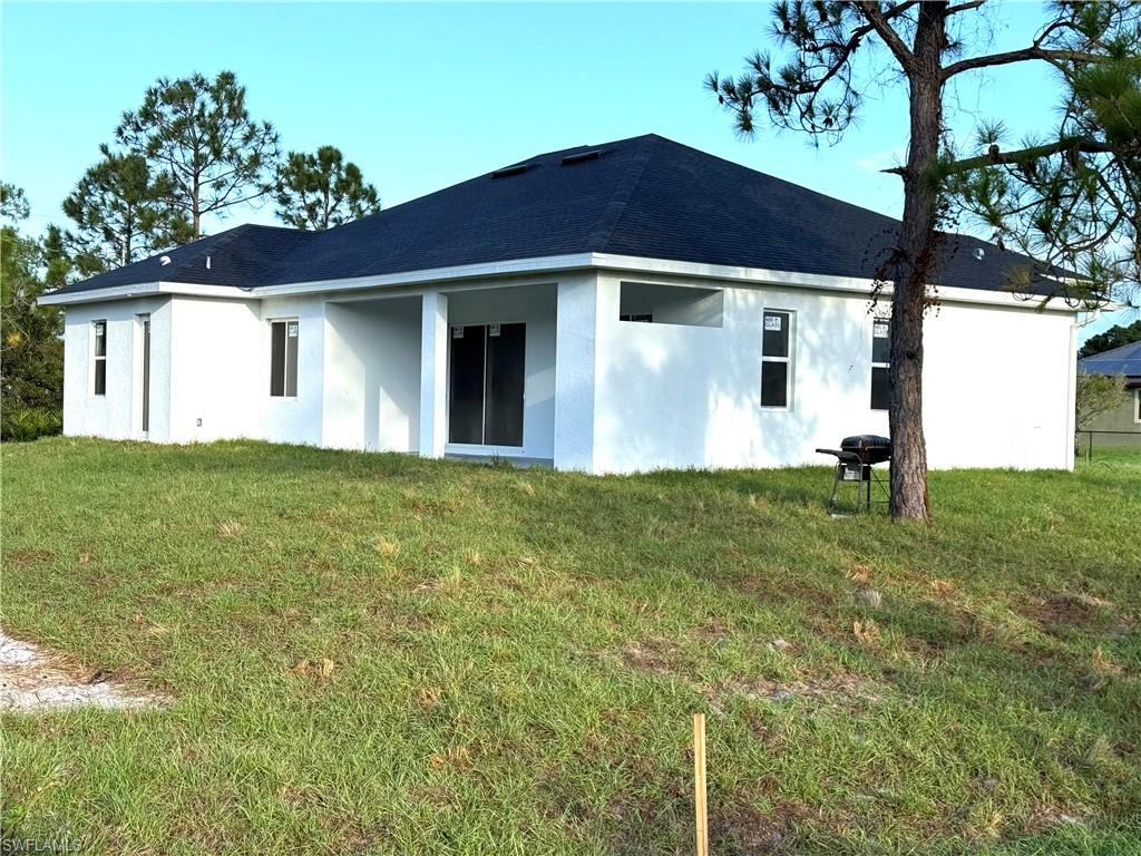 Rear view of property featuring stucco siding and a yard