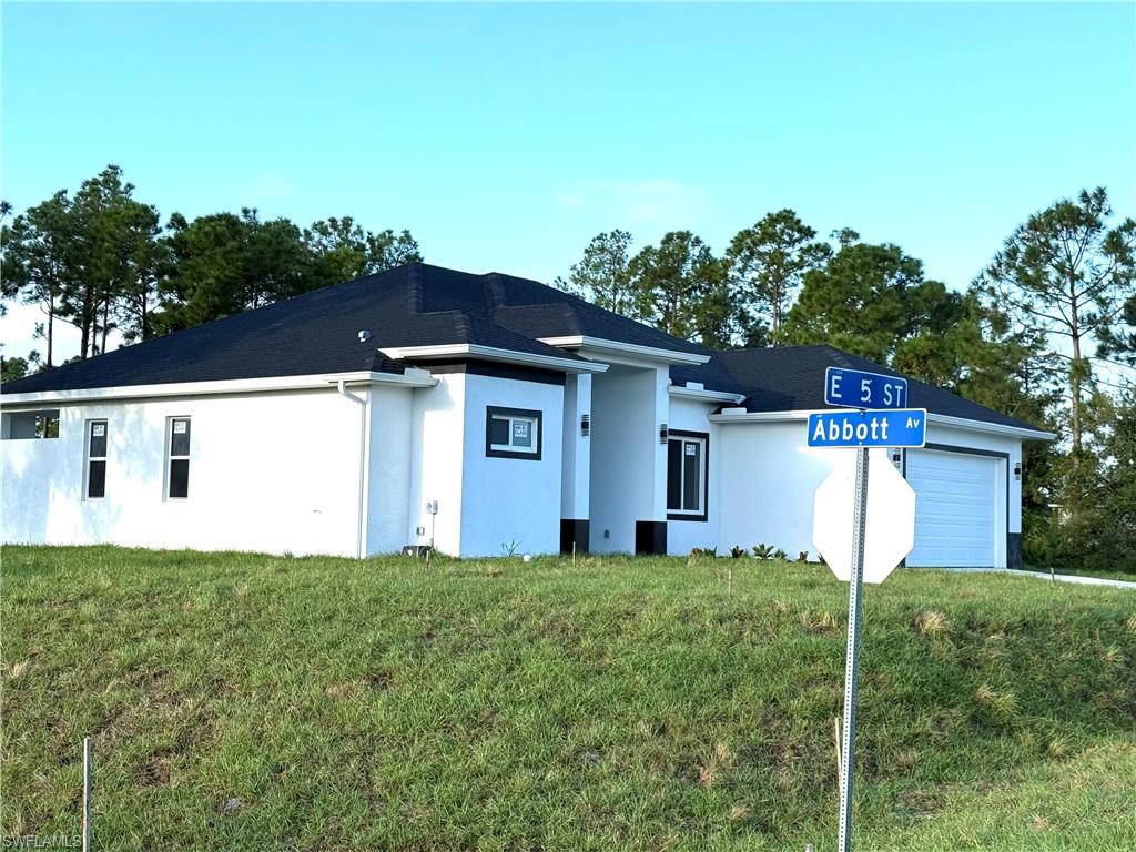 View of front facade with stucco siding, a front yard, and an attached garage