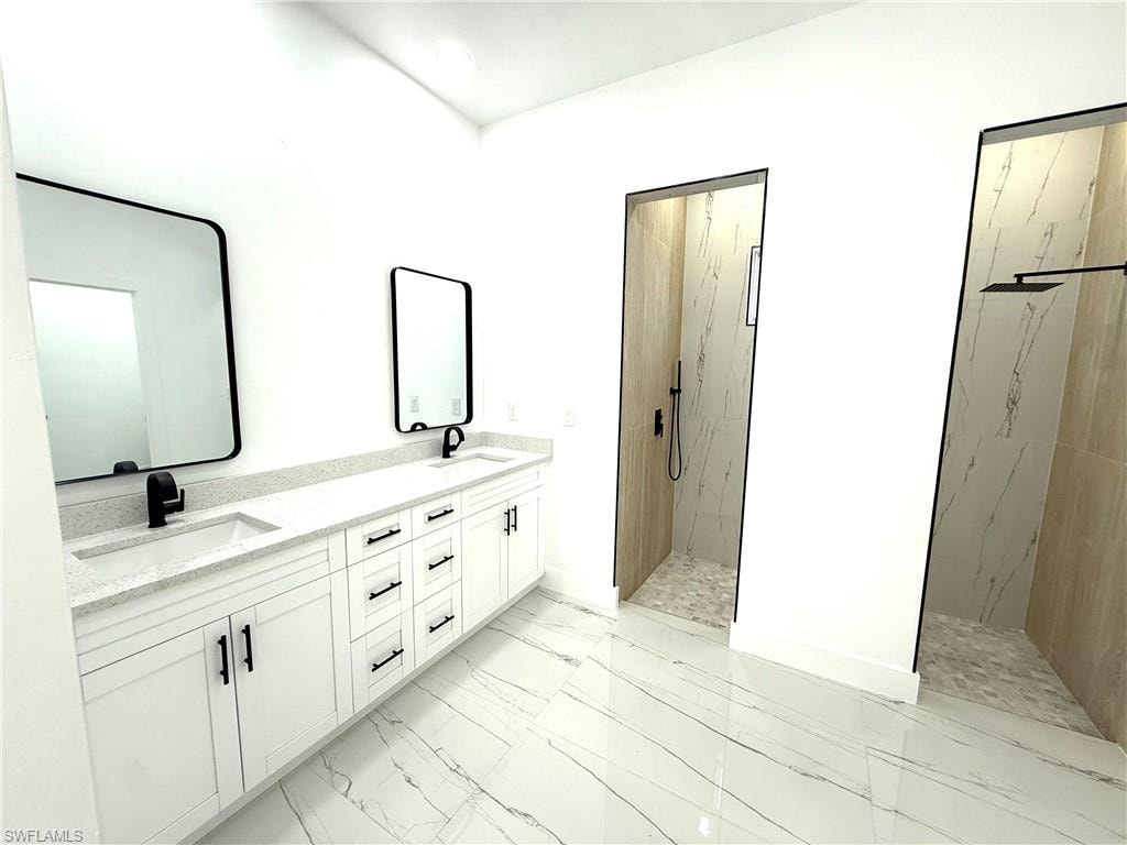 Full bathroom with a marble finish shower, double vanity, and light marble finish floors