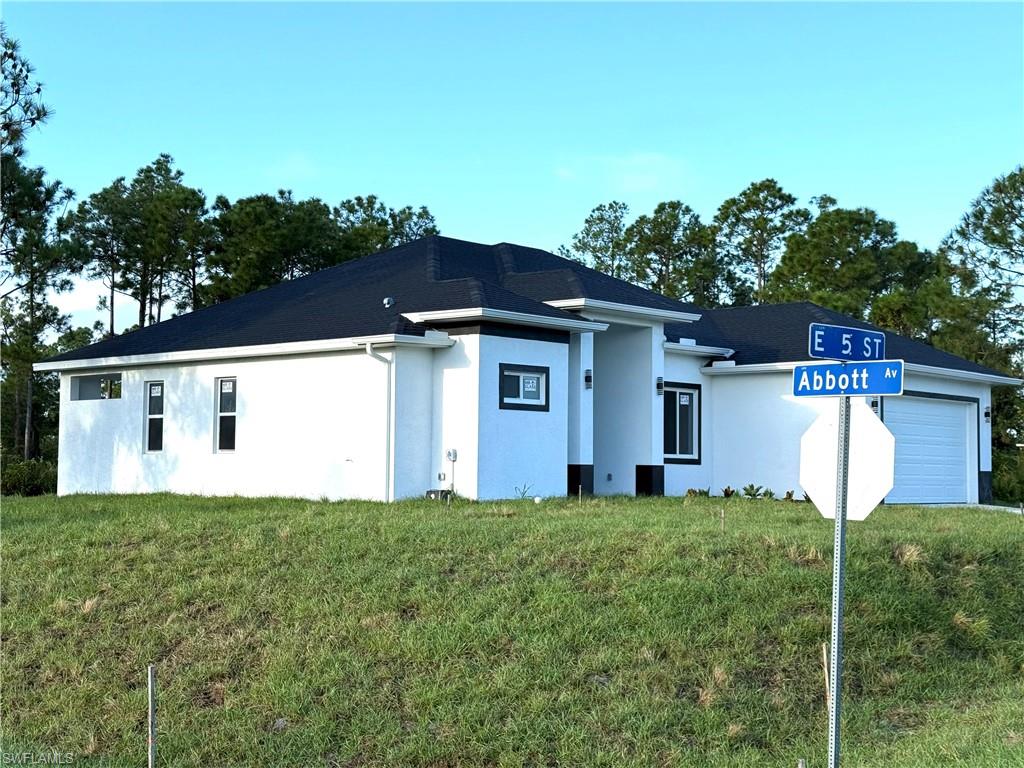 View of front facade featuring stucco siding, a front yard, and a garage