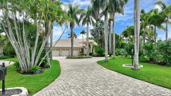View of front of property with a front lawn, a garage, and decorative driveway