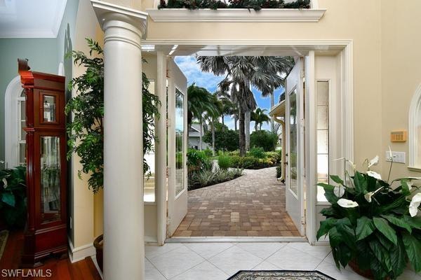Entryway with ornamental molding, tile patterned floors, and ornate columns