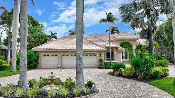 View of front of property with a tiled roof, a garage, stucco siding, and decorative driveway