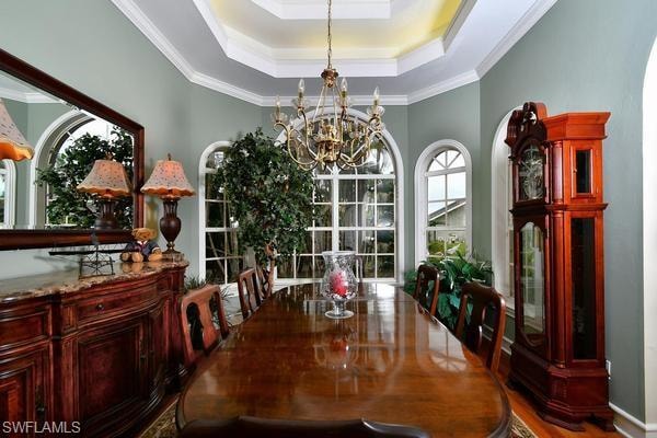 Dining room featuring a chandelier, a tray ceiling, crown molding, and wood finished floors