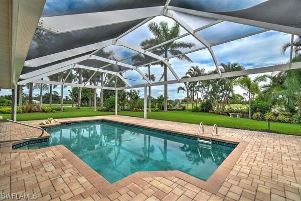 Swimming pool featuring glass enclosure, a patio, and a lawn