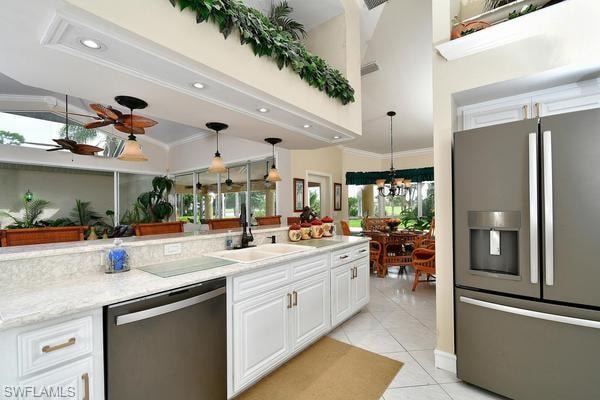 Kitchen featuring appliances with stainless steel finishes, white cabinets, pendant lighting, light tile patterned flooring, and light stone counters
