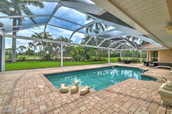 Swimming pool with a patio area, glass enclosure, a sunroom, and a yard