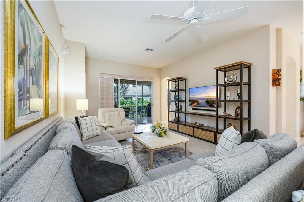 Tiled living area with ceiling fan and arched walkways
