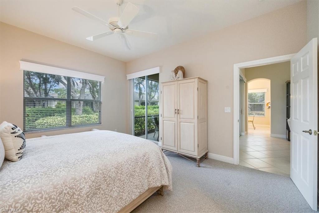 Bedroom featuring access to outside, light carpet, a ceiling fan, arched walkways, and light tile patterned floors