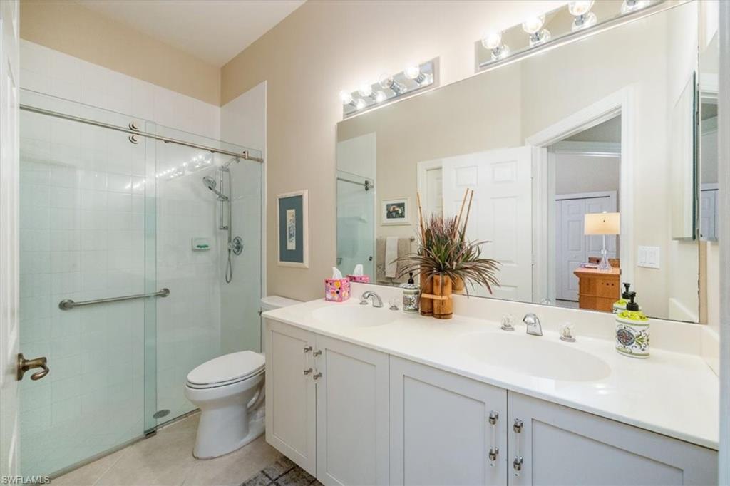 Full bath with a stall shower, double vanity, and light tile patterned floors