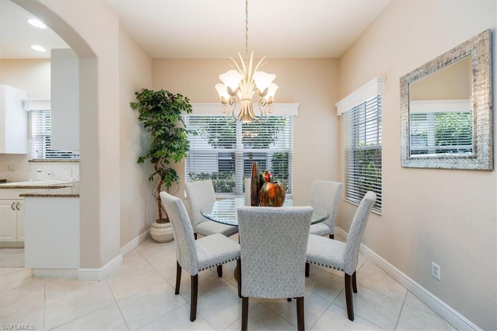 Dining room with light tile patterned floors, arched walkways, and a chandelier