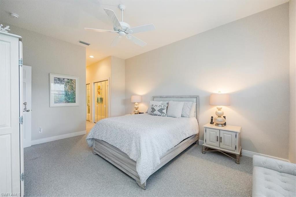Bedroom featuring light colored carpet, ceiling fan, and ensuite bathroom
