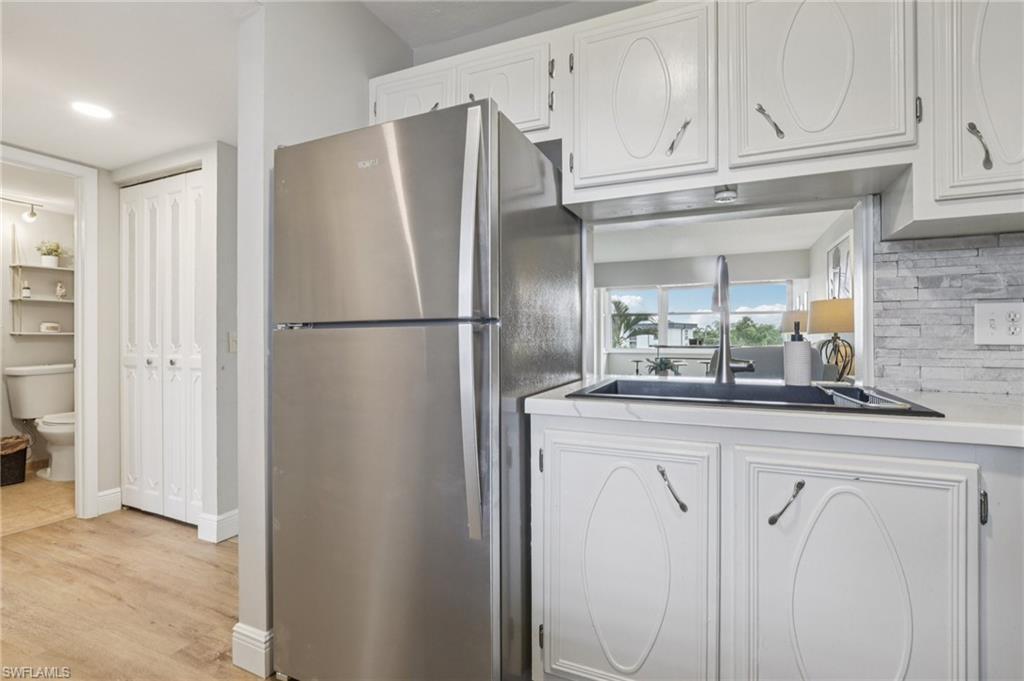 Kitchen with freestanding refrigerator, white cabinets, light countertops, tasteful backsplash, and recessed lighting