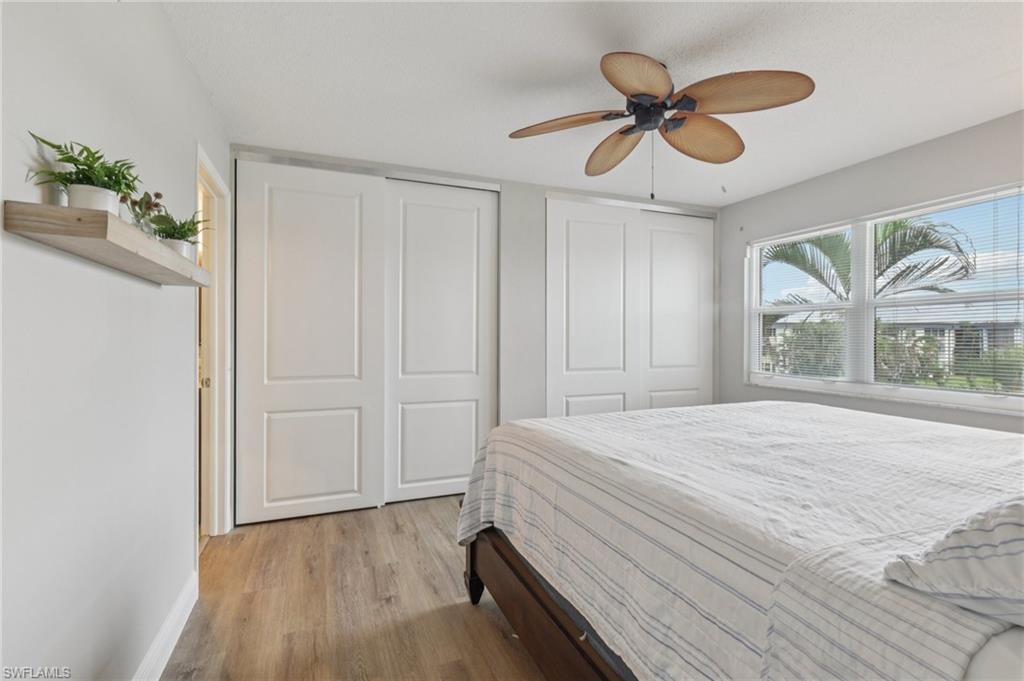 Bedroom with light LVP flooring, multiple closets, and a ceiling fan