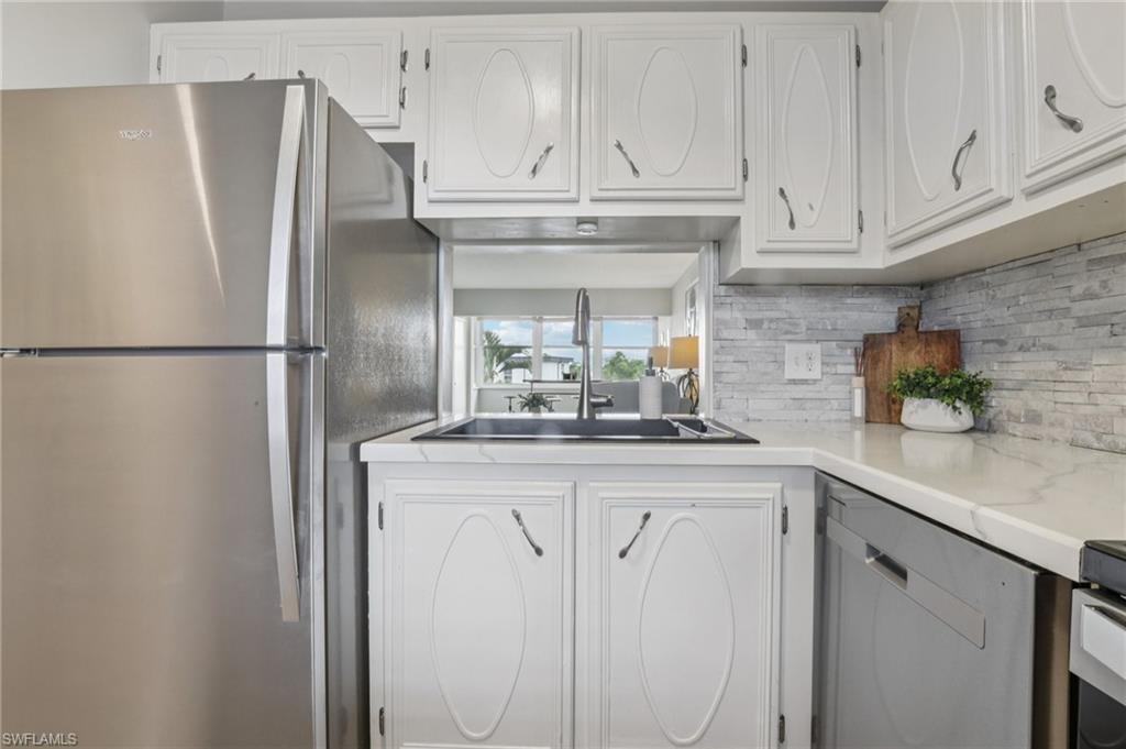 Kitchen featuring stainless steel appliances, white cabinets, tasteful backsplash, and light countertops