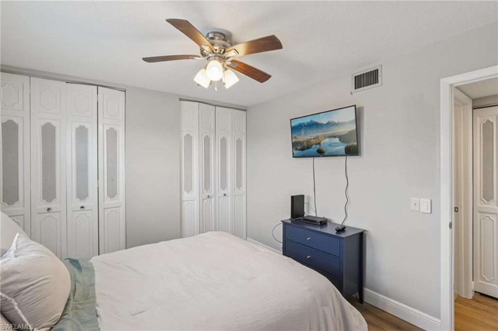 Bedroom with multiple closets, LVP floors, and a ceiling fan
