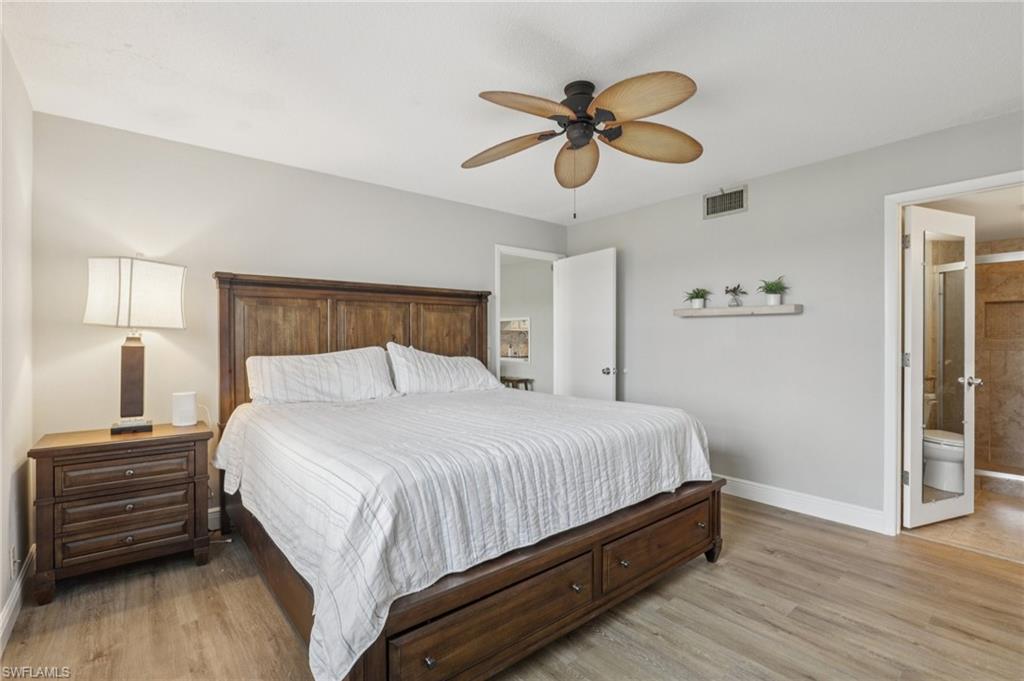 Bedroom featuring light LVP floors, ceiling fan, and ensuite bath