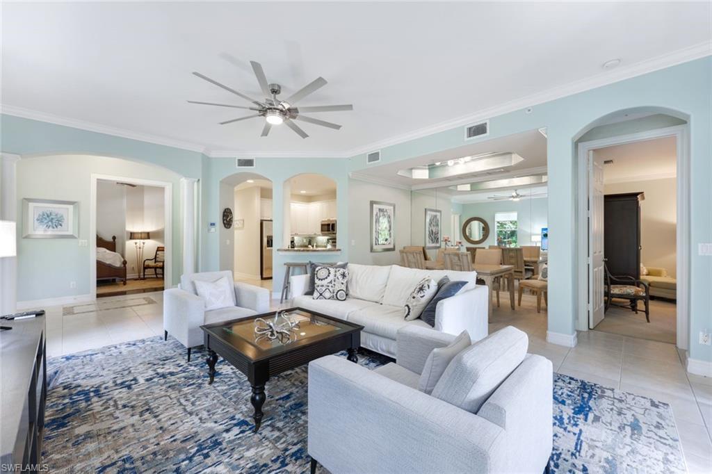 Living room with ornamental molding, ceiling fan, and light tile patterned floors