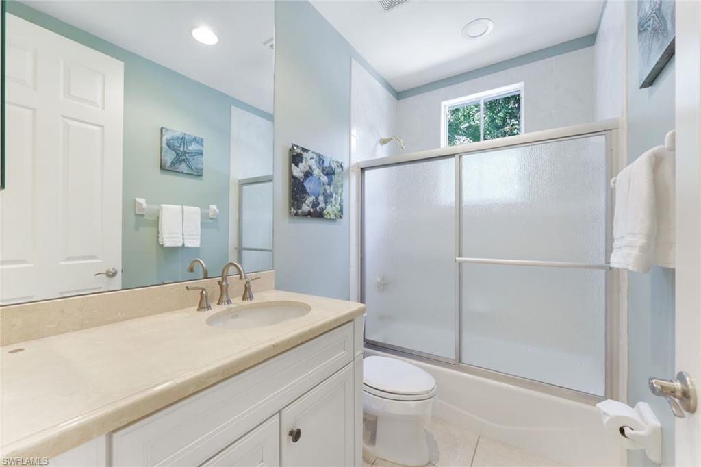 Full bathroom featuring vanity, tile patterned flooring, enclosed tub / shower combo, and toilet