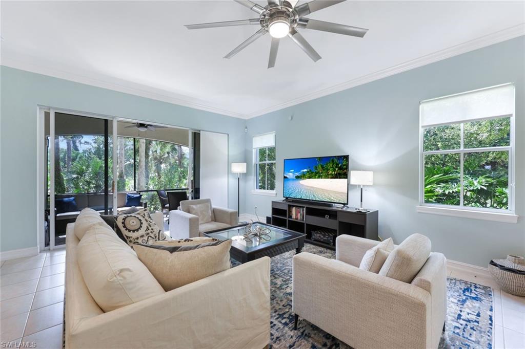 Tiled living room featuring ceiling fan and ornamental molding