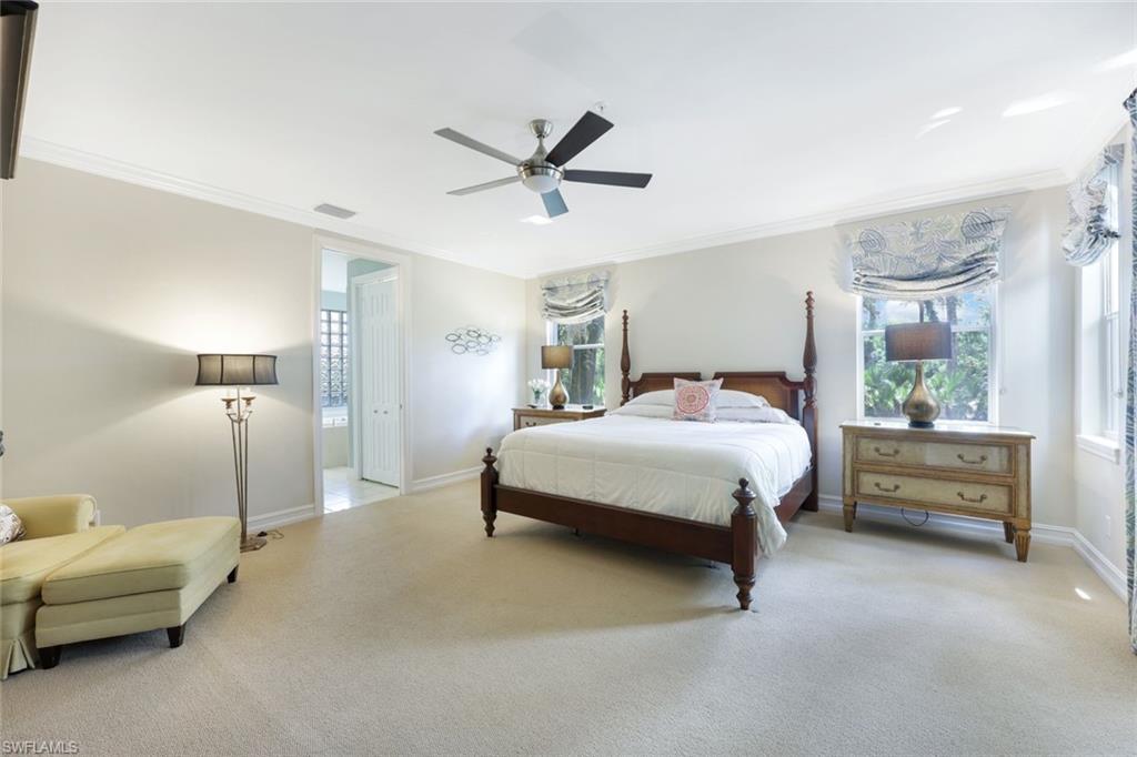 Carpeted bedroom featuring ceiling fan and crown molding