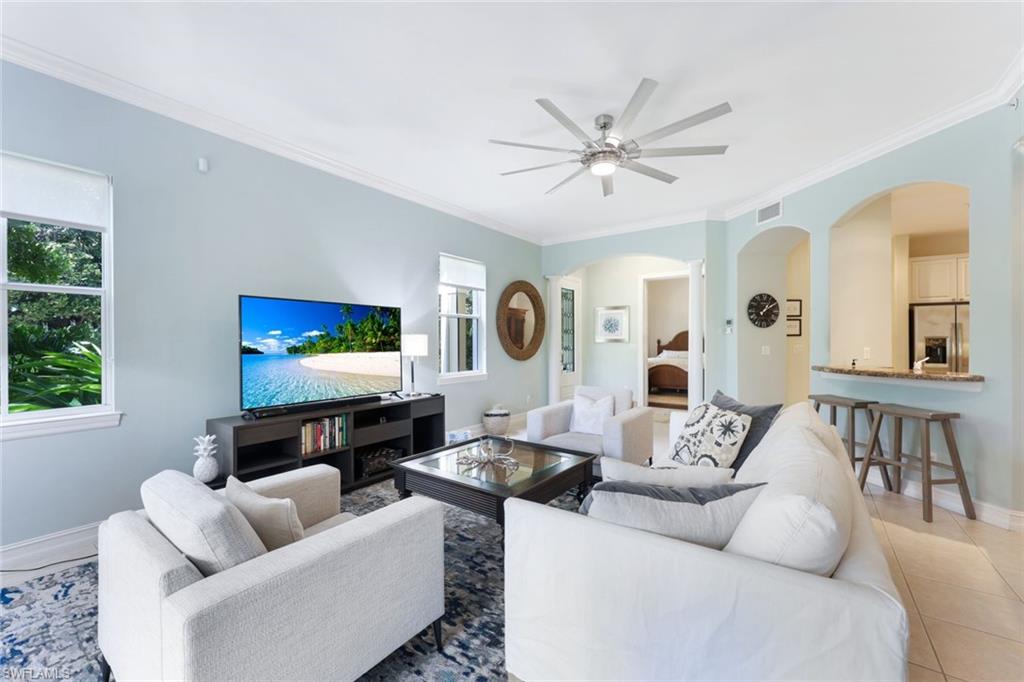 Tiled living room featuring crown molding, ceiling fan, and a wealth of natural light