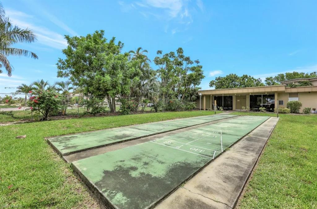 View of property's community featuring shuffleboard and a yard
