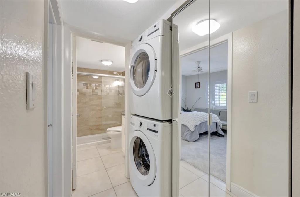 Laundry area featuring light tile patterned floors and stacked washer / drying machine