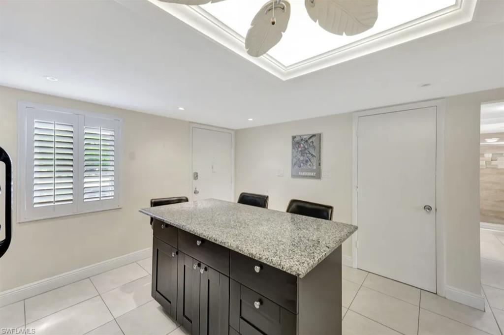 Kitchen featuring a ceiling fan, light stone countertops, light tile patterned flooring, a kitchen island, and recessed lighting