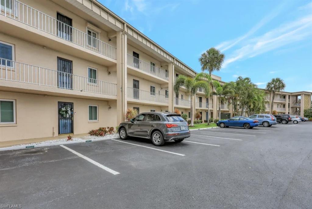 View of apartment building / complex featuring uncovered parking