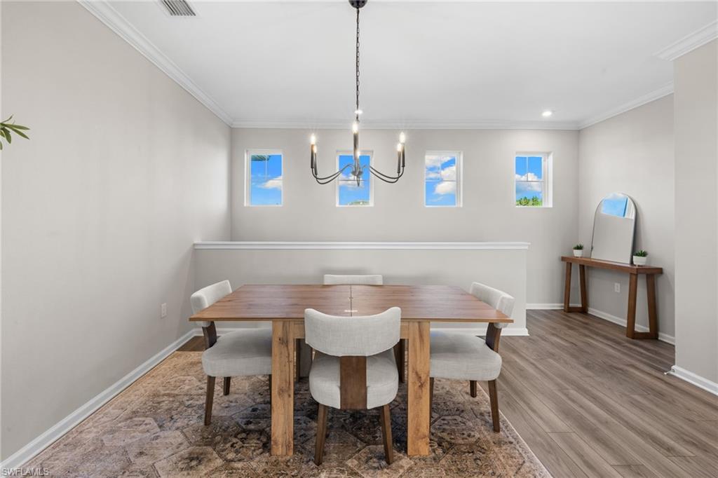 Dining area featuring ornamental molding, plenty of natural light, wood finished floors, and a chandelier