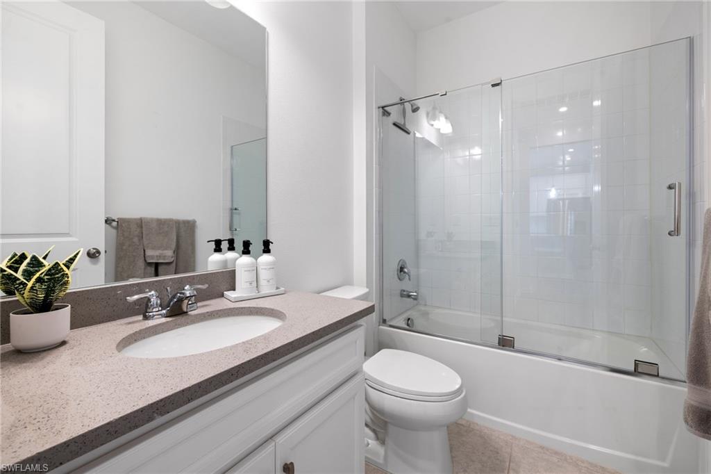 Full bathroom featuring combined bath / shower with glass door, vanity, and light tile patterned flooring