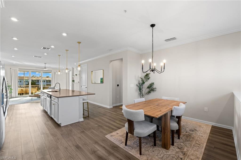 Dining area featuring recessed lighting, dark wood finished floors, crown molding, and a chandelier