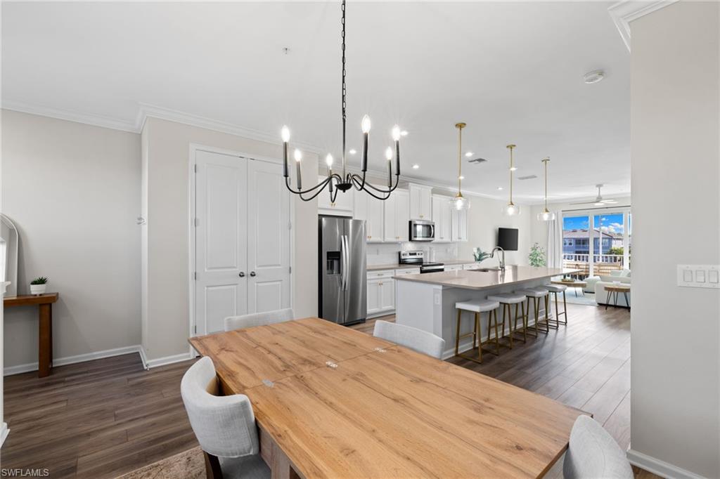 Dining area featuring dark wood-style floors, a chandelier, recessed lighting, ornamental molding, and a ceiling fan