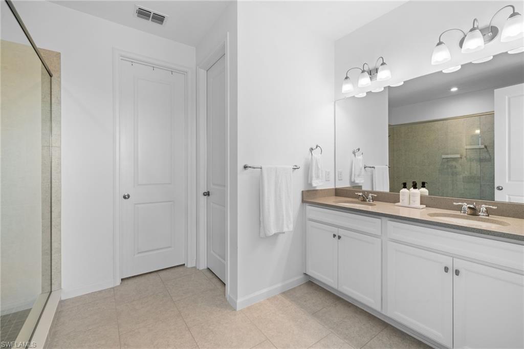 Full bath featuring a walk in shower, double vanity, and light tile patterned floors