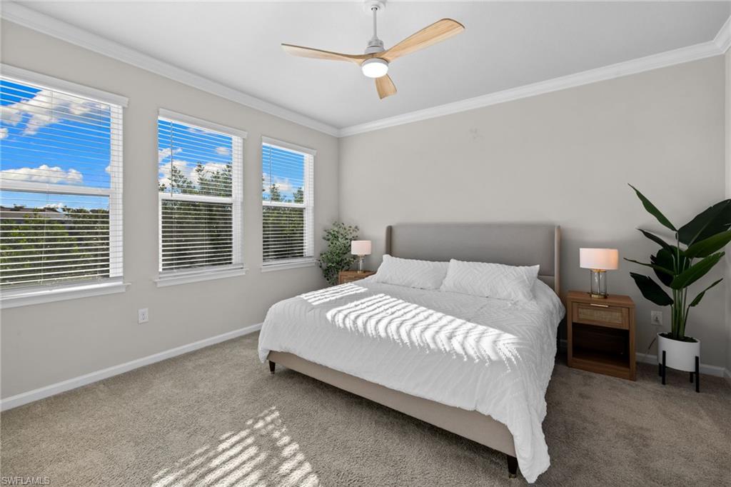 Carpeted bedroom with ornamental molding and a ceiling fan