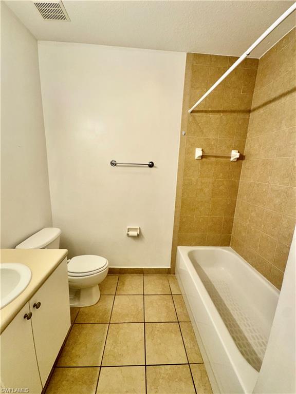 Bathroom with vanity, light tile patterned floors, shower / tub combo, and a textured ceiling