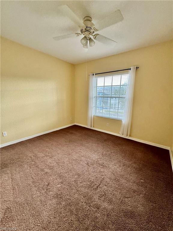 Empty room with carpet flooring and a ceiling fan